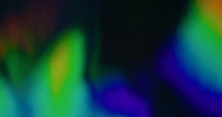 Blurred rainbow hologram. Foil wavy texture. Defocused leak multicolor green blue rays flickers beam gradient lens flare on art black dark background.