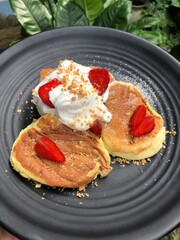 Homemade soufflé pancakes topped with ice cream, nuts and strawberries