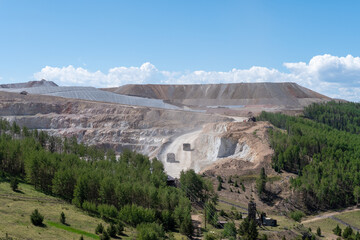 Expansive open pit gold mining operation in Colorado with heavy machinery working on a sunny day...