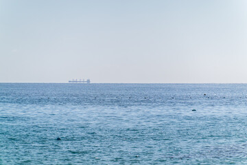 Calm blue sea with the silhouette of a large ship on the horizon