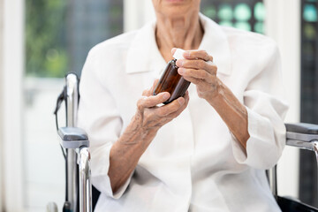 Hands of elderly holding bottle of medication,old senior reading medication instructions,carefully examining the label,taking capsules,pills,tablets,vitamin,supplement,health care,medical concept.