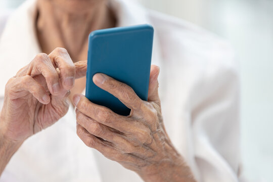 Closeup of hands,Asian senior woman using smartphone,old elderly holding mobile phone,concept of technology, financial deception,cybercrime,victim of scams,internet fraud,online scams, cyber threats