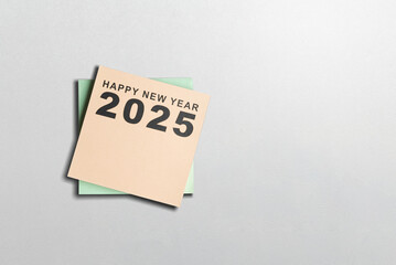 Top view of Happy New Year 2025 text written on a stack of notes paper with white background