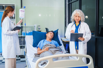 Two female doctors examine a patient lying on a hospital bed,discuss the medical chart,administer medicine,and provide encouragement, ensuring compassionate care and fostering the patient's recovery