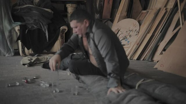 Drunk man barely stands.A drunk man has trouble getting up.Man drinking vodka alone in a dark room in slow-motion.
