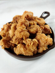 Heap of crispy fried chicken in a brown plate, isolated on white background with copy space. Close-up view