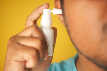 Close up of men using spray to remove earwax