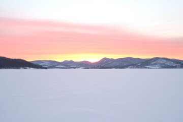 Fototapeta premium A beautiful sunset over a snow covered mountain range