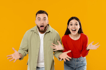 Obraz premium A joyful couple stands against a bright yellow background, both with wide smiles and surprised expressions. They are excited and share a moment of happiness and connection.