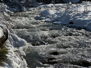 Naklejka premium A river in a mountainous area in winter. A stormy stream.