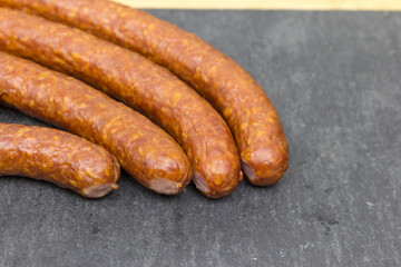 The hunting sausages are on a black Cutting board. food preparation cutting.