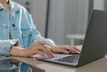 Close-up of businessman hand holding young woman typing on laptop computer with digital tablet on desk. Manager searching for information. Business and technology. Paperless office.