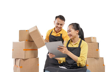 A female courier smiles as she shows a tablet to a male courier and sits in front of a pile of boxes.