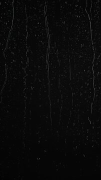 Vertical water rainfall, rain drops falling on window glass on black background