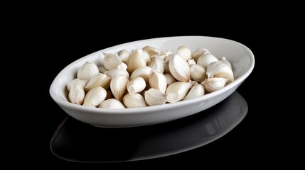 Pieces of white garlic in a bowl on black glass.