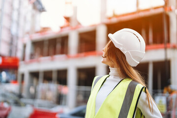 Female construction worker oversees building site progress in urban environment during daylight