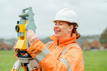 Smiling woman surveyor operating equipment outdoors in a clearing on a cloudy day