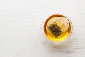 Cup of hot tea blended from rooibos, spearmint, apple, baobab on white wooden table.