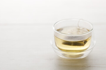 Cup of hot tea blended from rooibos, spearmint, apple, baobab on white wooden table.