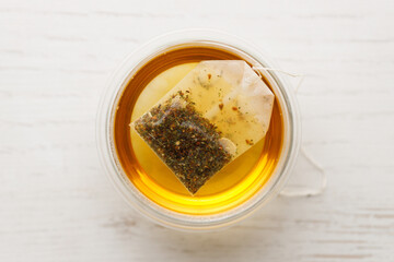 Cup of hot tea blended from rooibos, spearmint, apple, baobab on white wooden table.