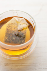 Cup of hot tea blended from rooibos, spearmint, apple, baobab on white wooden table.
