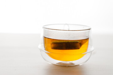 Cup of hot tea blended from rooibos, spearmint, apple, baobab on white wooden table.