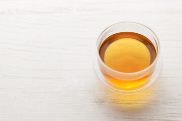 Cup of hot tea blended from rooibos, spearmint, apple, baobab on white wooden table.