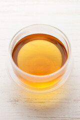 Cup of hot tea blended from rooibos, spearmint, apple, baobab on white wooden table.