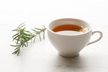 Cup of hot tea blended from rooibos, spearmint, apple, baobab on white wooden table.
