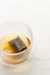 Cup of hot tea blended from rooibos, spearmint, apple, baobab on white wooden table.