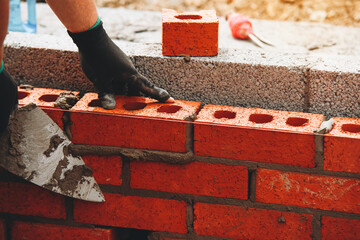 Bricklayer Expertly laying red bricks for a sturdy wall in a construction project in bright daylight