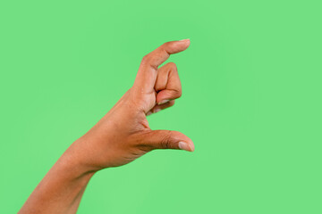 Hand gesture of a pinch on a bright green background illustrating a concept of smallness in a creative way