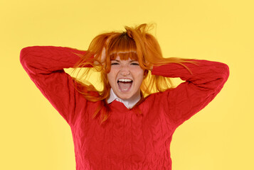 Young woman with vibrant orange hair expressing joy against bright yellow background while wearing...