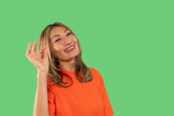 Woman smiling and gesturing delicious food  with hand against a green background in a cheerful...