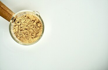 Green coffee powder food ingredients in small glassware cup pot isolated on horizontal copy spaced white background.