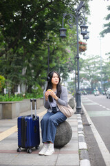 Young Asian Woman Eating Street Food While Sitting on The City Street