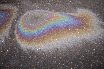 Rainbow gasoline or oil spill creating colorful sheen on asphalt road surface