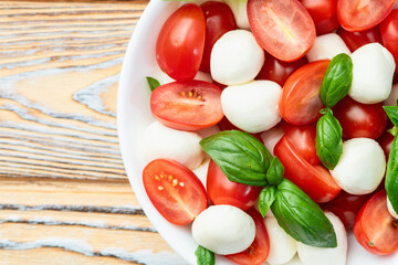 Basil leaves , cherry tomatoes and mozzarella cheese . In bowl food photography