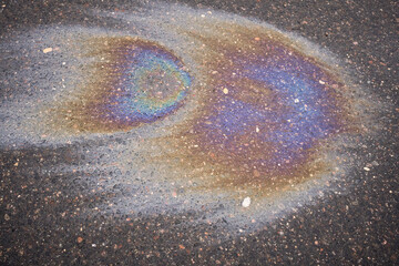 Colorful gasoline or oil spill creating a rainbow sheen on asphalt road surface