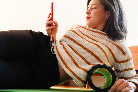 A woman is lying on a massage roller with a red phone in her hands