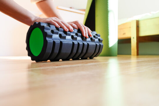Close-up of hands holding a black massage roller in a home interior