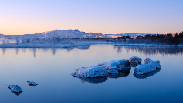 Tranquil lake reflecting snowy mountains during the serene dusk