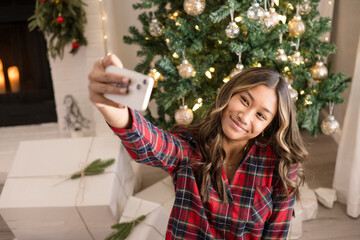 Girl taking a selfie in front of the christmas tree