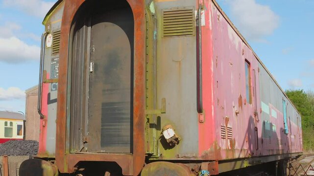Profile view of old train wagon not in use on railway track during daytime.