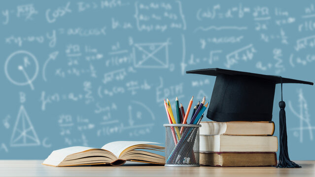 Education learning concept. A mortarboard and graduation scroll on stack of books with pencils color in a pencil case on chalkboard background.