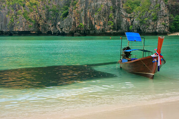 Longtail boat anchored at Maya Bay next to school of fish on Phi Phi Leh Island, Krabi Province, Thailand