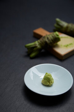 Grater and grated horseradish on a black stone baking sheet