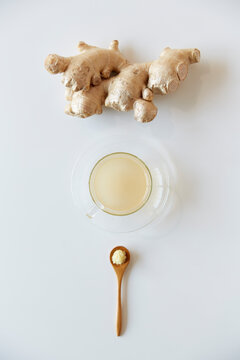 Spoon with large ginger and grated ginger on it and ginger tea