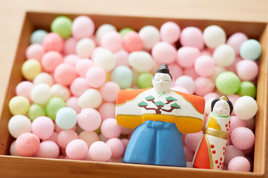 Hina dolls and arare in a bowl on a wooden tabletop