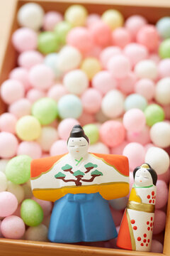 Hina dolls and arare in a bowl on a wooden tabletop